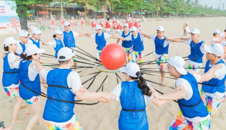 Đội chơi trò giữ bóng lớn bằng dây đai ngoài bãi biển – Minh họa rõ nét cho _Đồng tâm hiệp lực_ hoặc các trò phối hợp nhịp nhàng